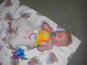 Chewing on lion while playing on her Noah's ark blanket.