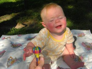 Phoebe playing in the park, reaching for her rattle.