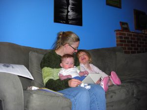 Mommy reads a birthday card with her two little pumpkins.