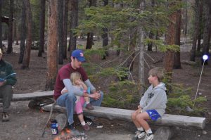 Phoebe sitting with Jason while he plays cards with Oliver.