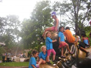 Isabelle, Kylie, Phoebe, and Elisa climb a statue at the zoo. 