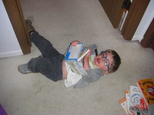 Lying in the hallway reading a book.