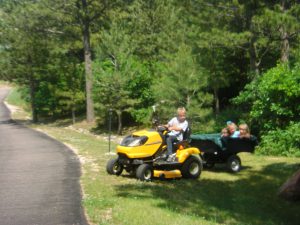 Logan Lafont pulling his sister Leah, Phoebe, and Benjamin with the tractor.