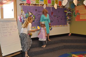 Miss Cheryl presents Phoebe with her kindergarten diploma.